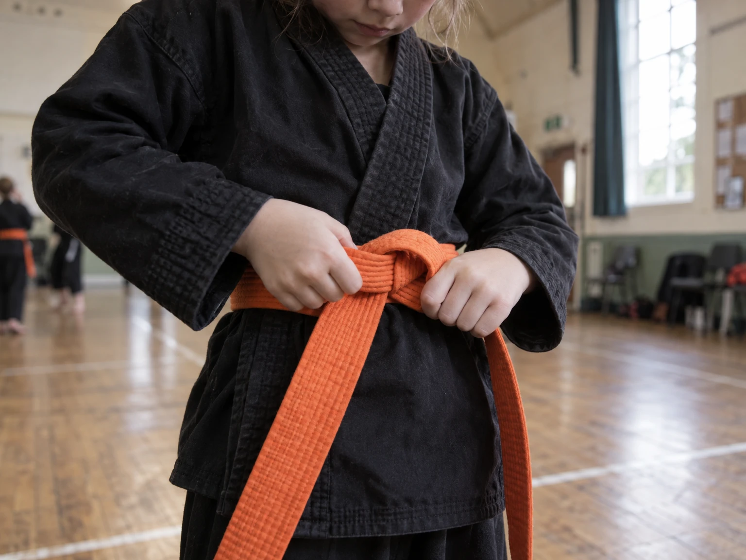 A child tying an orange belt